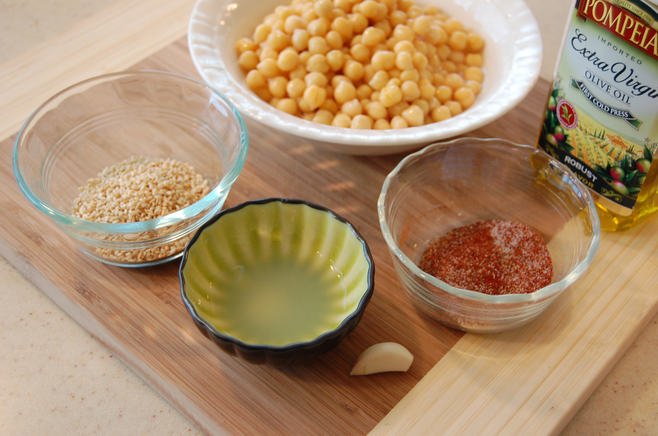 DSC_1456 Garbanzo beans, olive oil, garlic, sesame seeds, and seasonings on a cutting board.