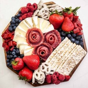 Adding yogurt pretzels and raspberries to a charcuterie board.