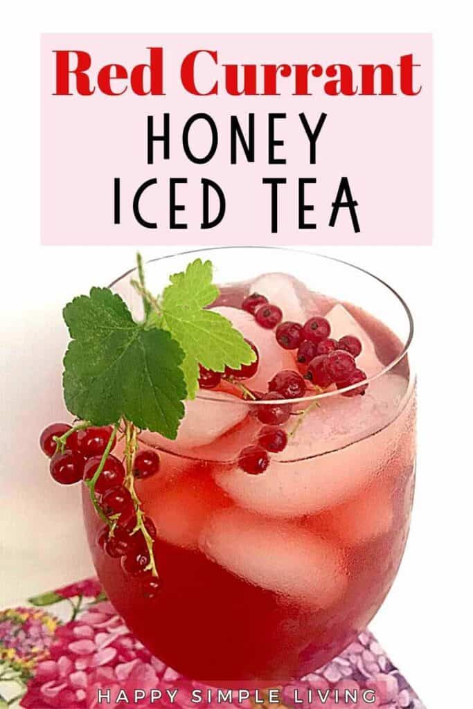A glass of red currant honey iced tea filled with ice cubes, garnished with fresh red currants and a green leaf. The image has text that reads Red Currant Honey Iced Tea at the top and Happy Simple Living at the bottom.