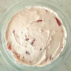 Strawberry cheesecake dip spread in a clear glass serving dish.